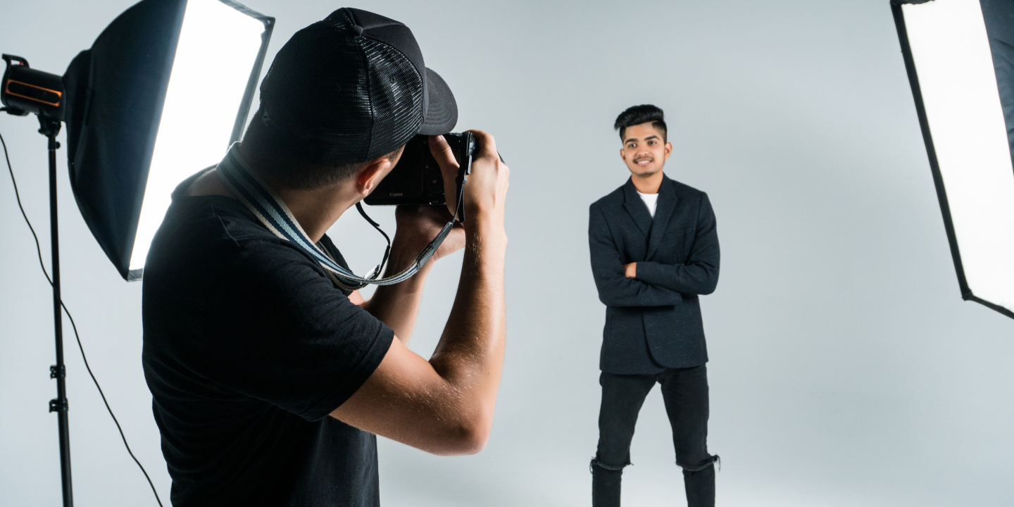 Ein professioneller Fotograf macht ein Foto von einem jugnen Mann im Sakko