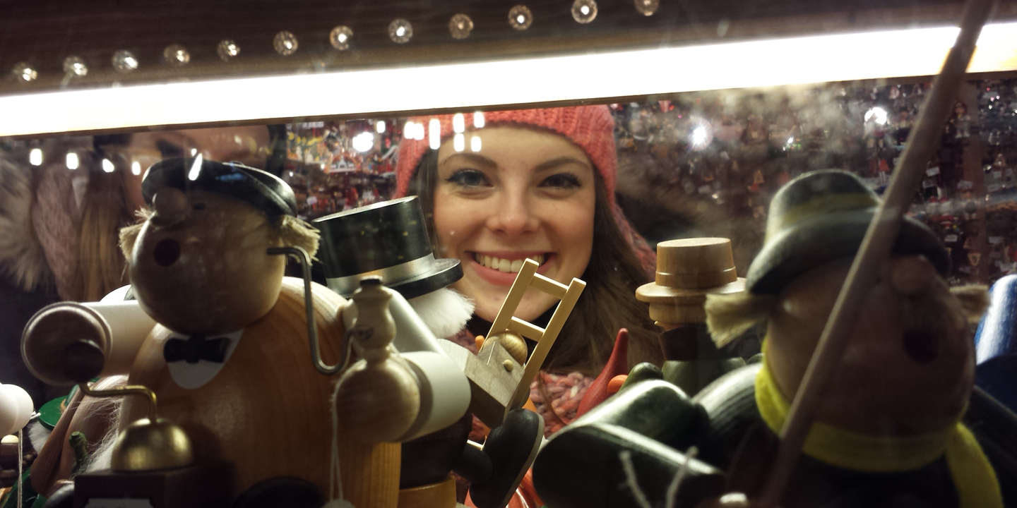 Ein Mädchen schaut ins Schaufenster eines Weihnachtsmarktstandes.