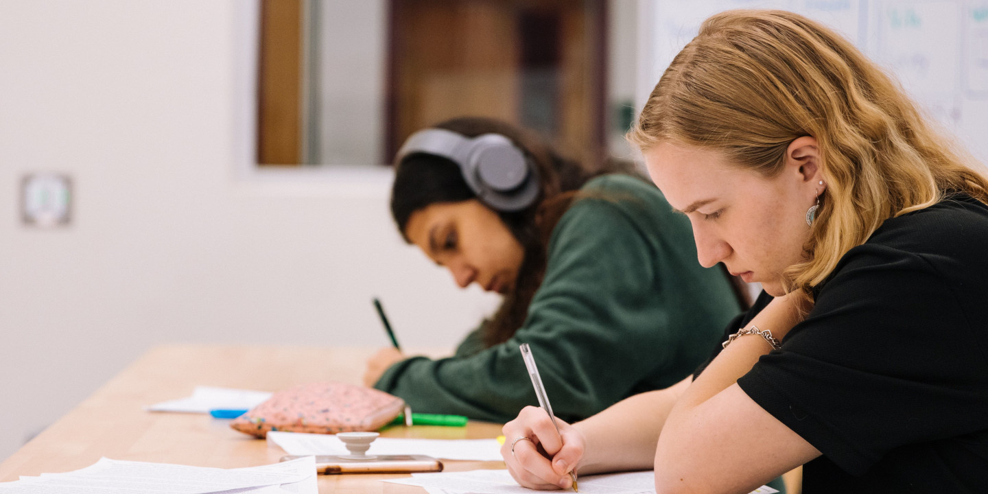 Zwei Jugendliche sitzen vor Aufgaben und schreiben einen Test.
